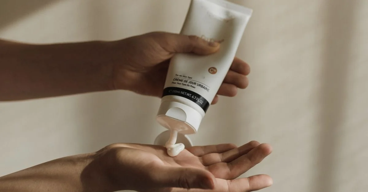 Gros plan sur une femme pressant de la lotion sur sa main, mettant en évidence les soins de la peau et la routine de soin personnel.