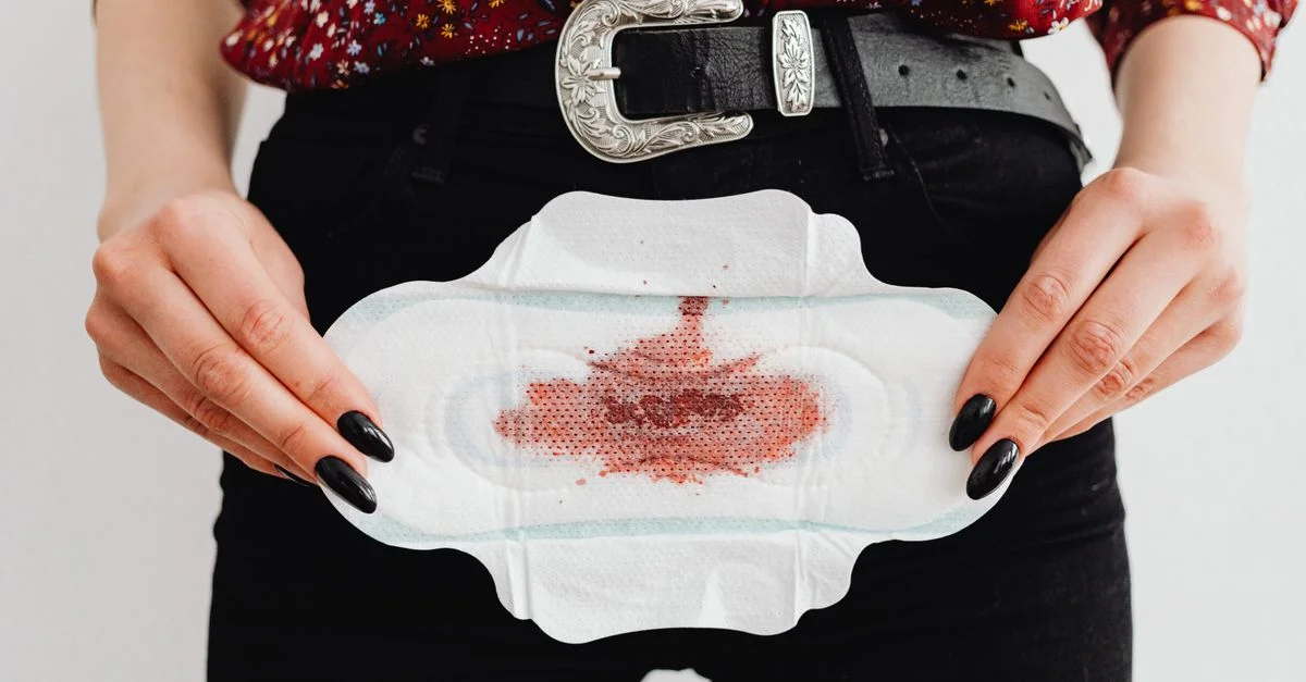 Vue en gros plan d'une femme tenant une serviette menstruelle tachée, mettant en avant la sensibilisation à la menstruation.