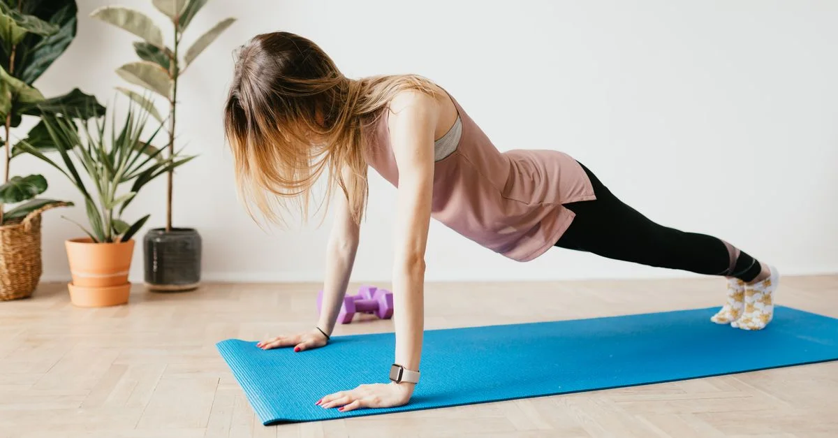 Une femme réalisant la position de planche sur un tapis dans un environnement domestique serein avec des plantes.